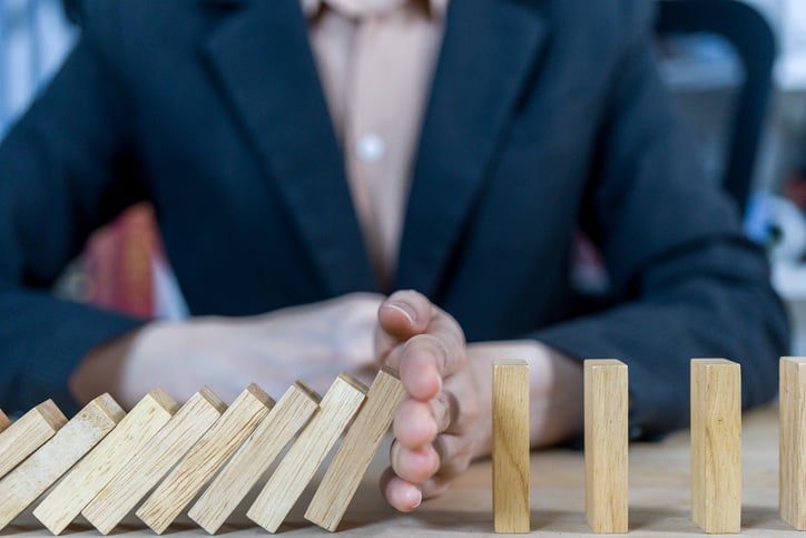 Risk management- hands stopping dominoes from falling over